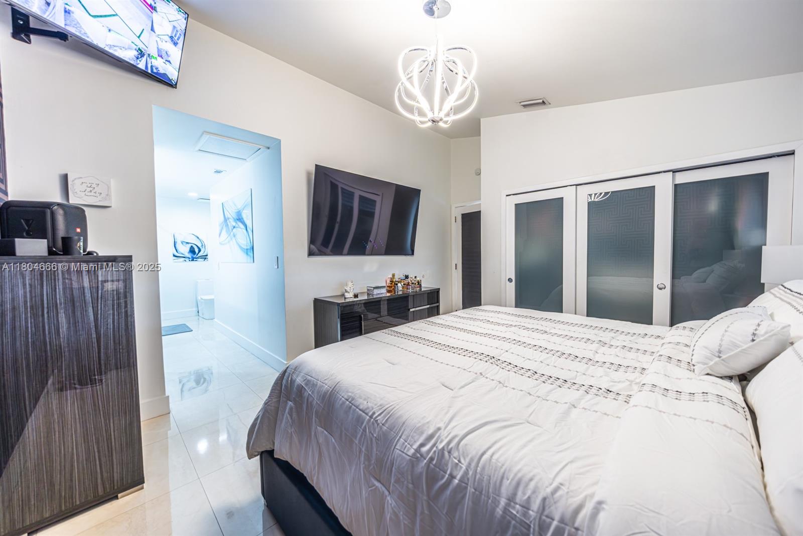 6950 Northwest 168th Street Hialeah, FL 33015 - Photo 24 of 28 a spacious bedroom with a bed and a flat tv screen on dresser