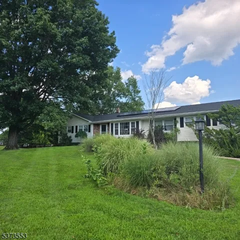 a view of a big house with a big yard and large trees