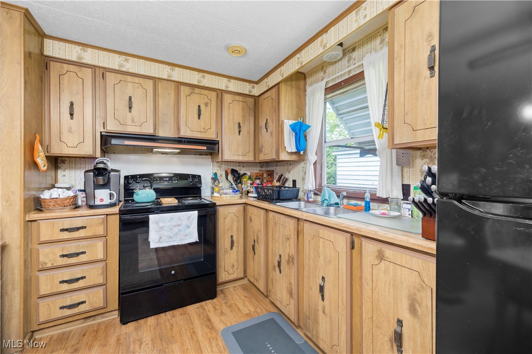 35157 Center Ridge Road, Unit 117 North Ridgeville, OH 44039 - Photo 12 of 21 Kitchen with black appliances, under cabinet range hood, a sink, light countertops, and light wood-type flooring