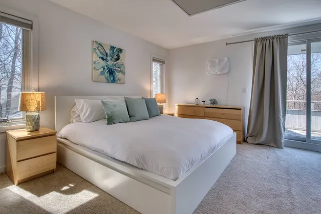 a bedroom with a bed painting on wall and a large window