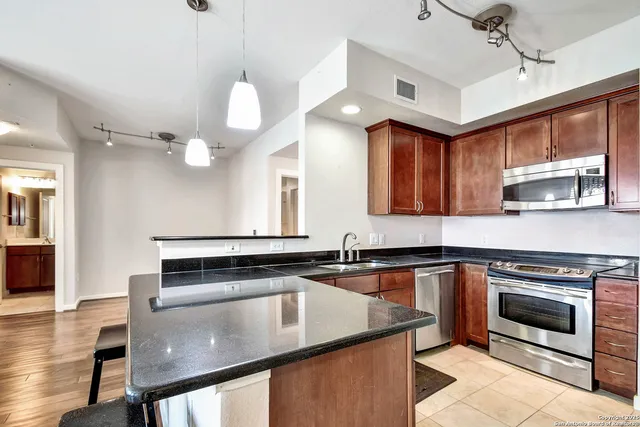 a kitchen with stainless steel appliances granite countertop a stove a sink and a microwave