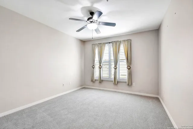 an empty room with windows and ceiling fan