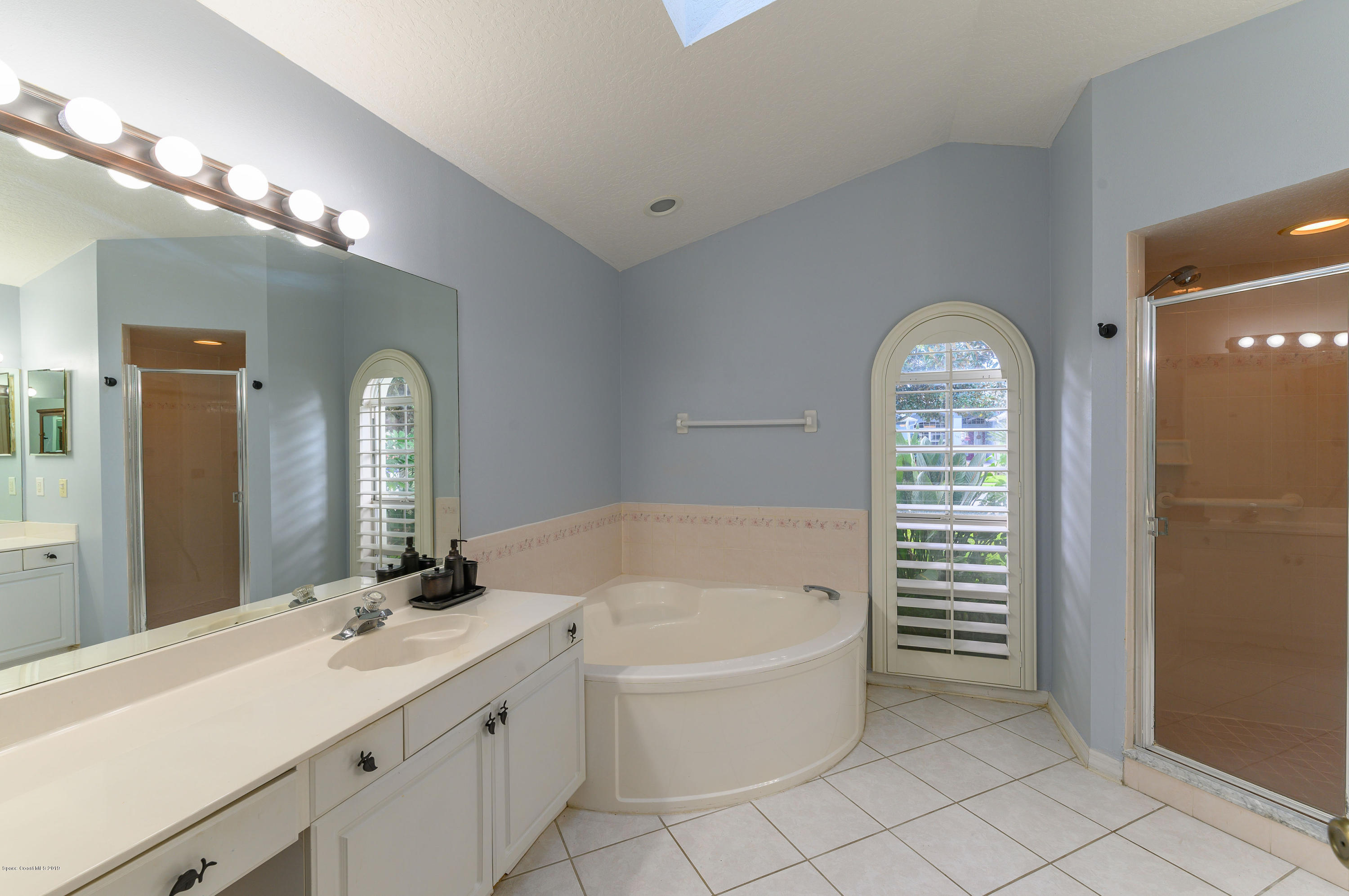 1256 Winding Meadows Road Rockledge, FL 32955 - Photo 12 of 23 a bathroom with a tub a double vanity sink and a mirror
