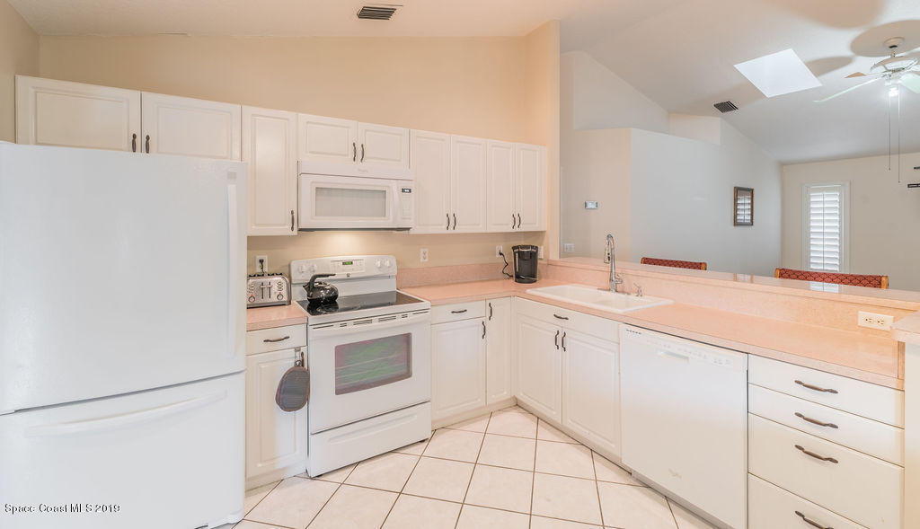 1256 Winding Meadows Road Rockledge, FL 32955 - Photo 5 of 23 a kitchen with white cabinets and white appliances
