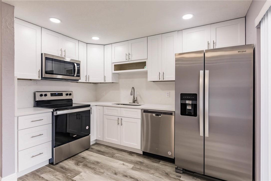 209 Woodland Road Palm Springs, FL 33461 - Photo 9 of 23 a kitchen with stainless steel appliances granite countertop a refrigerator stove a sink and a microwave