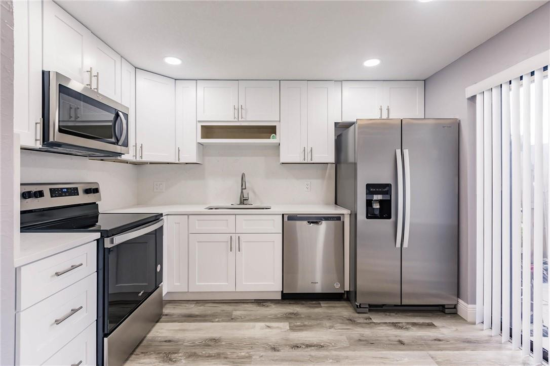 209 Woodland Road Palm Springs, FL 33461 - Photo 10 of 23 a kitchen with stainless steel appliances and white cabinets