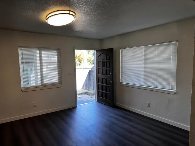 an empty room with wooden floor and windows