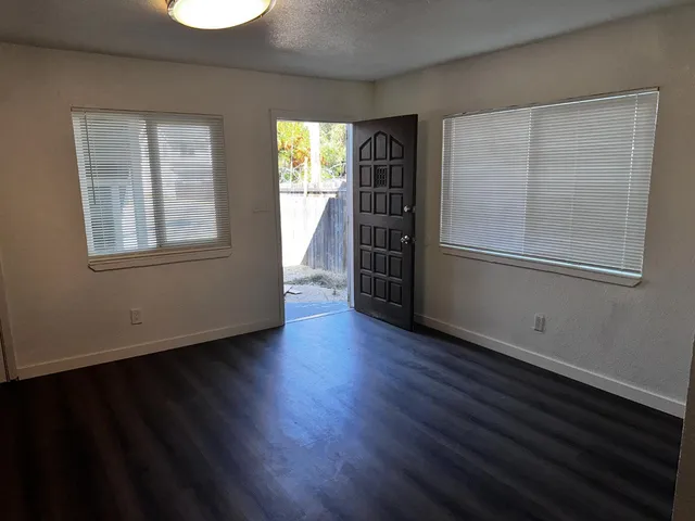 an empty room with wooden floor and windows