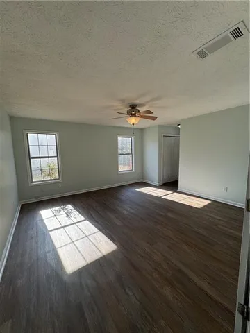 an empty room with wooden floor and windows