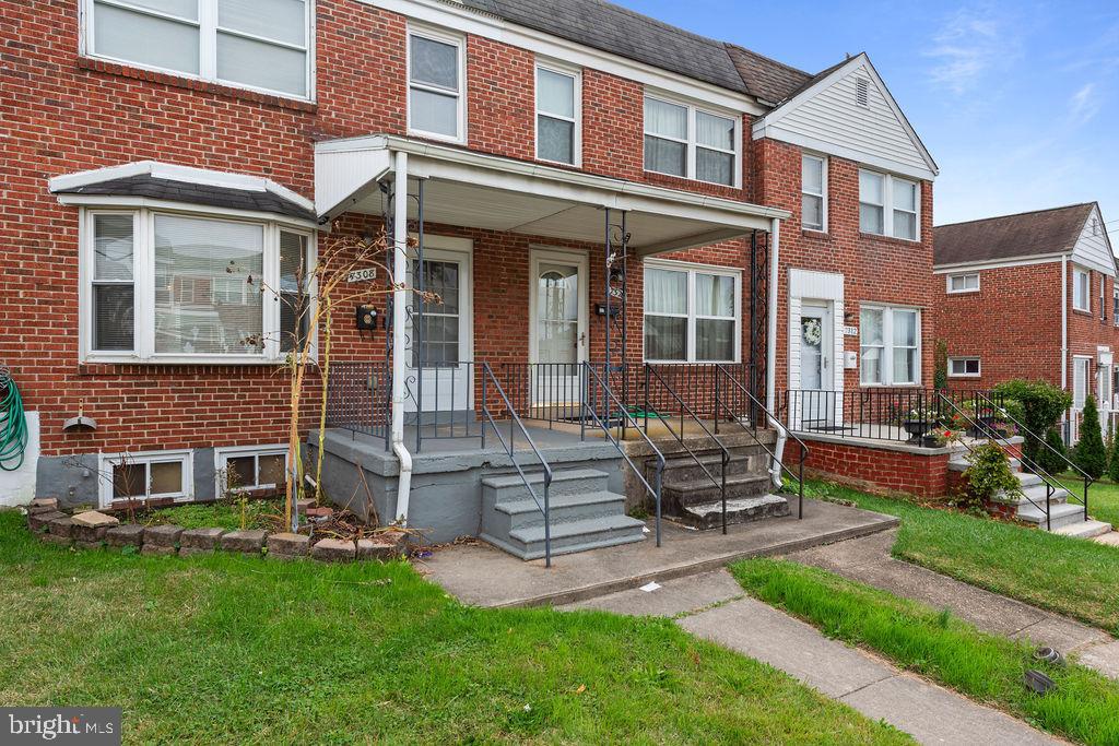 7308 Berkshire Road Baltimore, MD 21224 - Photo 3 of 40 front view of a brick house with a yard and table and chairs