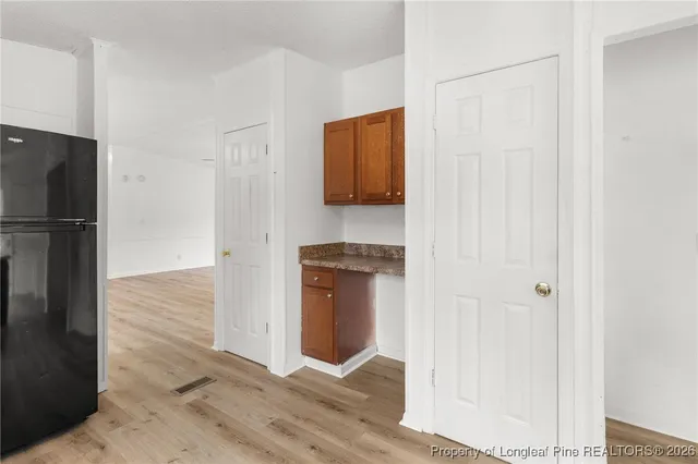 a hallway with wooden floor and a refrigerator