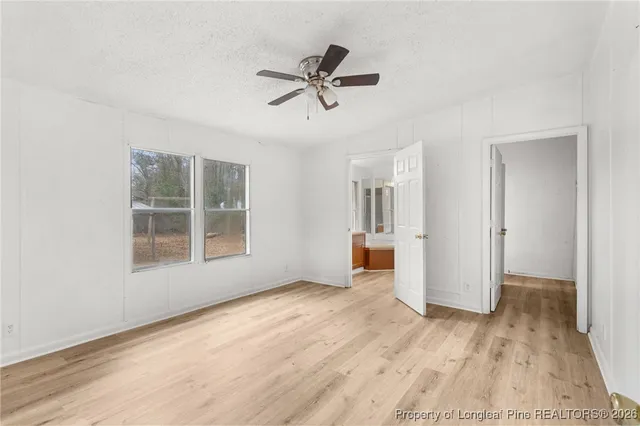 a view of empty room with wooden floor and ceiling fan