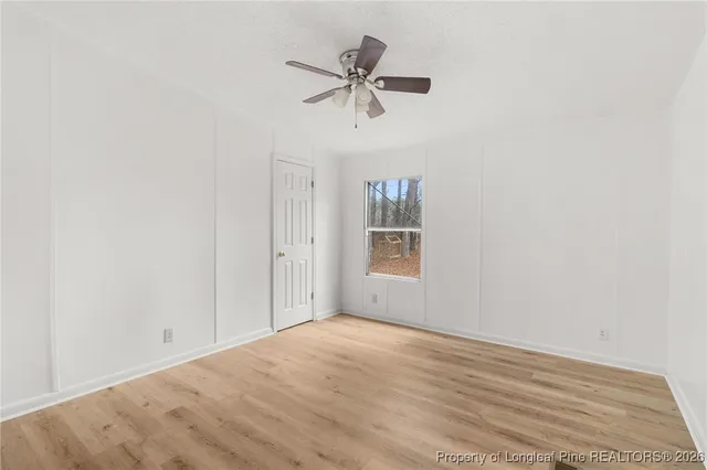 a view of empty room with window and ceiling fan