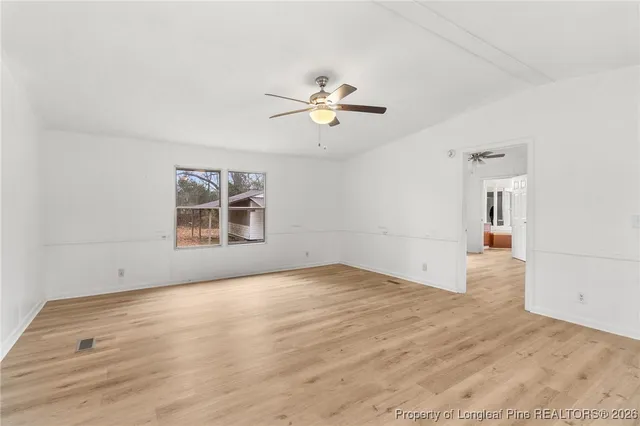 a view of empty room with wooden floor and ceiling fan