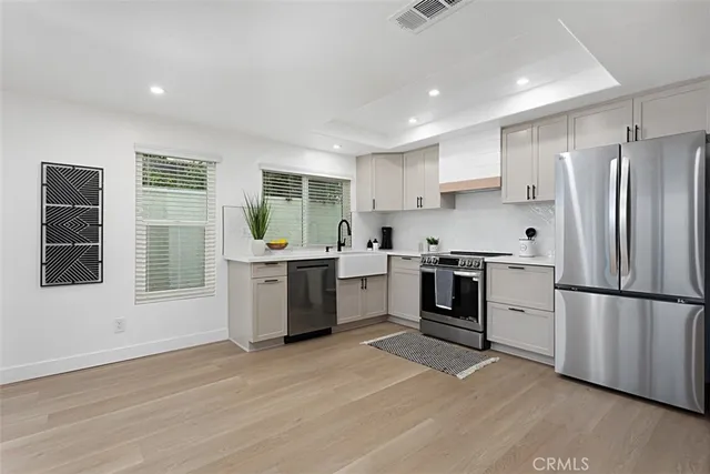 a kitchen with a white stove top oven cabinets a refrigerator and a window