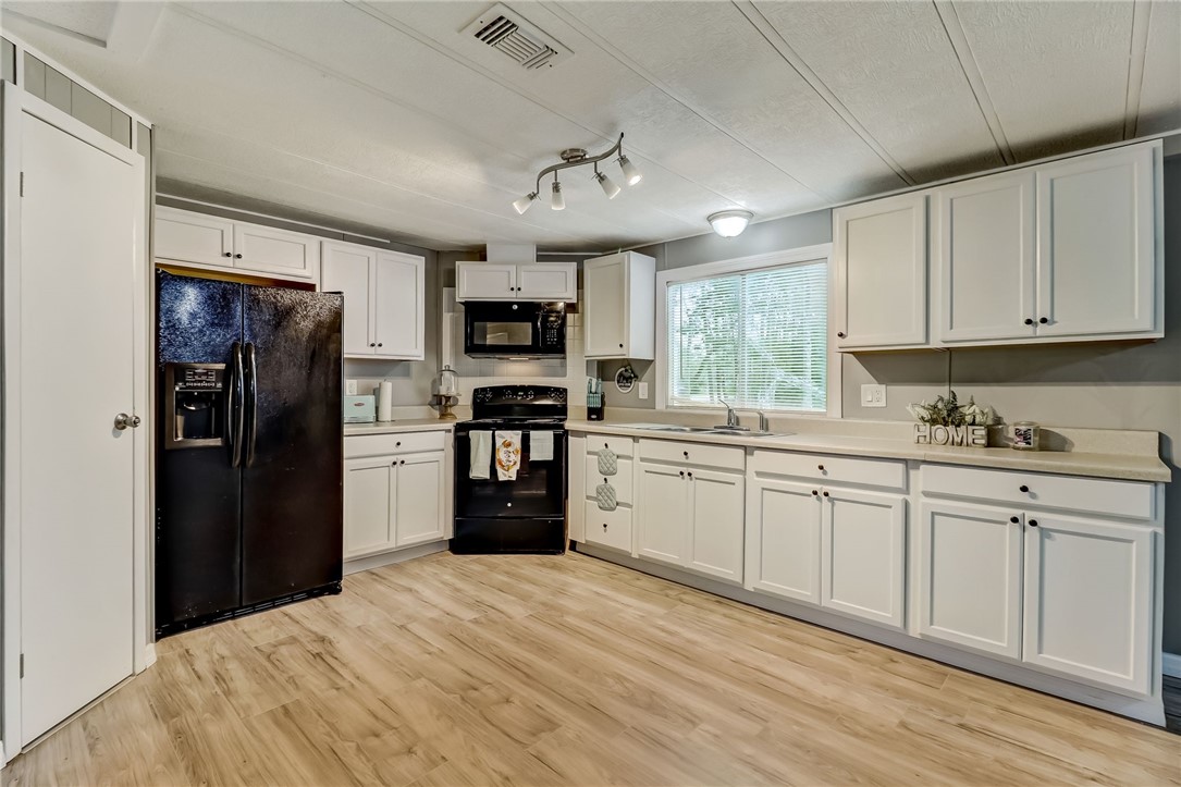 540821 Lem Turner Road Callahan, FL 32011 - Photo 4 of 35 a kitchen with granite countertop a refrigerator a sink dishwasher a stove and white cabinets with wooden floor