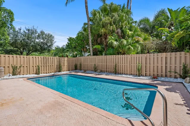 a view of a backyard with swimming pool and wooden fence