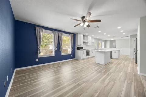 a view of an empty room with window and wooden floor