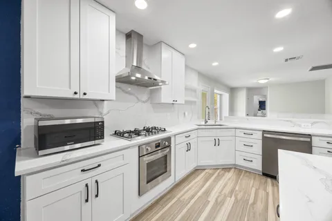 a kitchen with white cabinets stainless steel appliances and sink