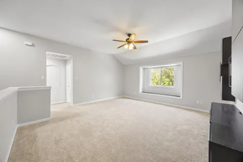 an empty room with windows and a chandelier fan