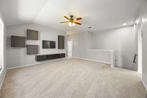 a view of an empty room with a ceiling fan and window