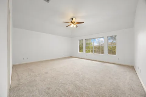 an empty room with windows and ceiling fan