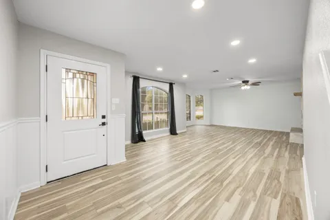 a view of an empty room with wooden floor and a window