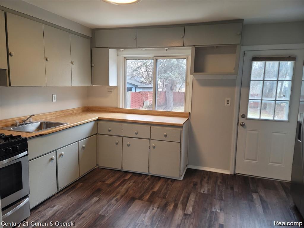 25906 Lehigh Street Inkster, MI 48141 - Photo 3 of 9 Kitchen featuring wood-finish flooring, a stainless steel sink, a window over the sink, and a rear exterior door with a window