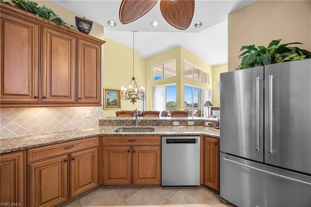 a kitchen with stainless steel appliances granite countertop a refrigerator a sink a stove and white cabinets