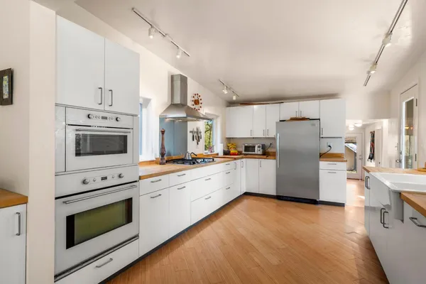 a large white kitchen with a large window and stainless steel appliances