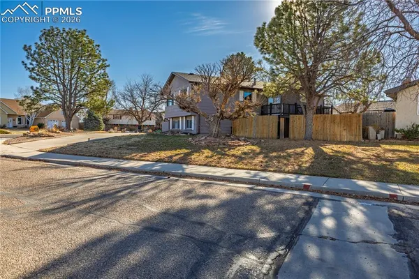 a backyard of a house with large trees and wooden fence