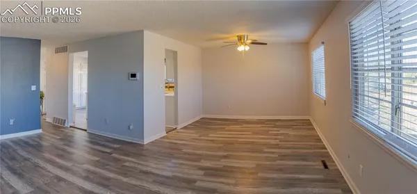 a view of an empty room with wooden floor fireplace and a window