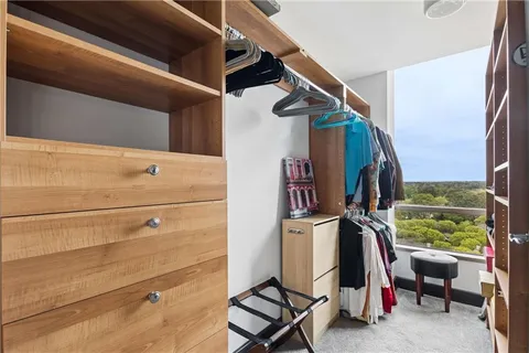 a view of walk in closet with clothes and shoes
