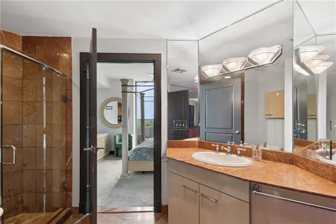 a bathroom with a granite countertop sink a mirror and shower
