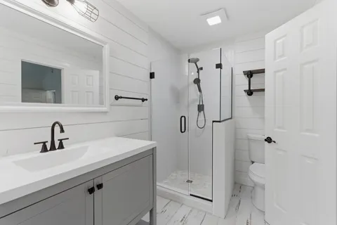 a bathroom with a shower sink vanity and toilet