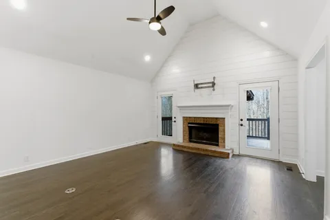 an empty room with wooden floor fireplace and windows