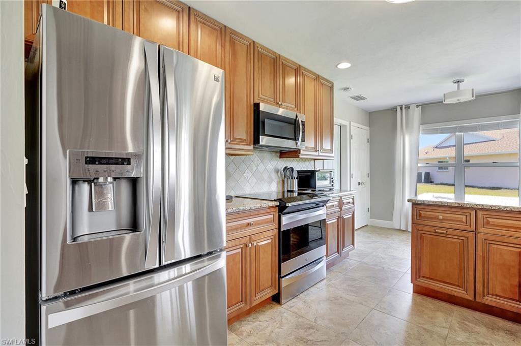 112 Versailles Circle Naples, FL 34112 - Photo 12 of 50 a kitchen with stainless steel appliances granite countertop a refrigerator stove and sink