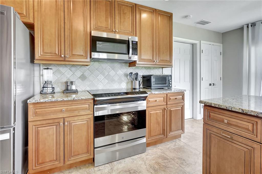 112 Versailles Circle Naples, FL 34112 - Photo 14 of 50 a kitchen with stainless steel appliances granite countertop a stove microwave and cabinets