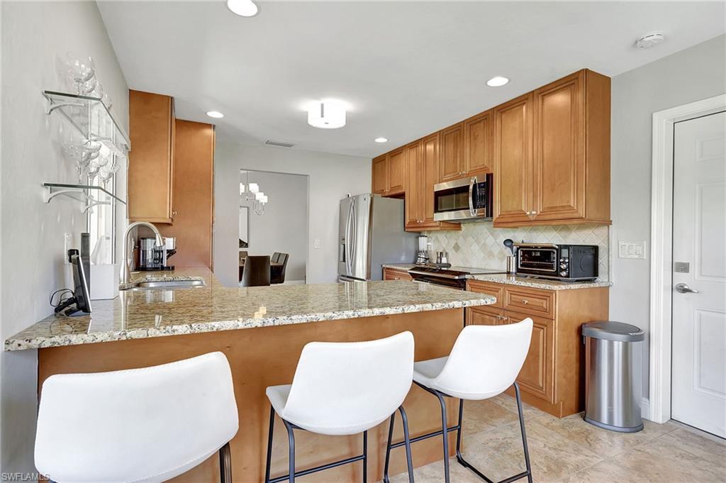 112 Versailles Circle Naples, FL 34112 - Photo 16 of 50 a kitchen with granite countertop a refrigerator and microwave