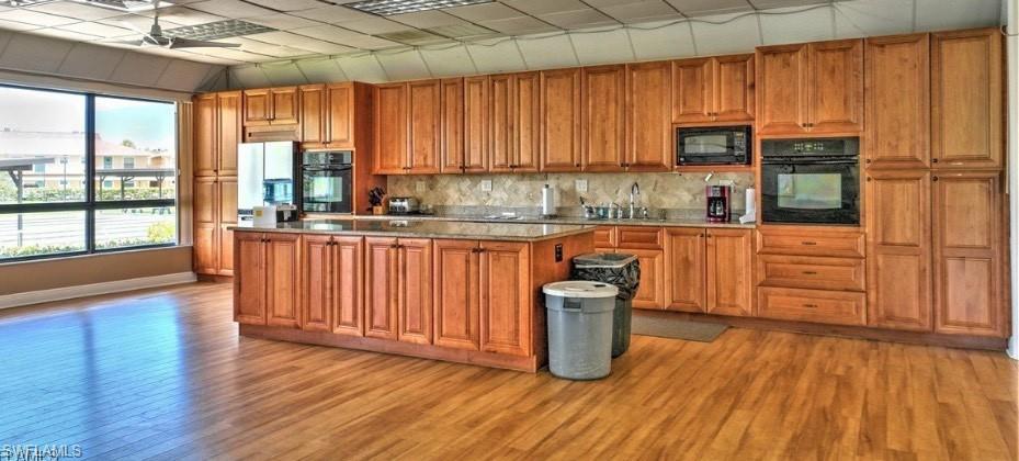 112 Versailles Circle Naples, FL 34112 - Photo 41 of 50 a kitchen with wooden floors and wooden cabinets