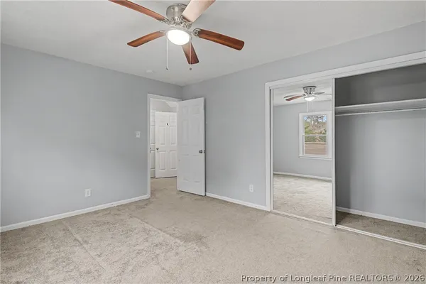 an empty room with closet and a chandelier fan