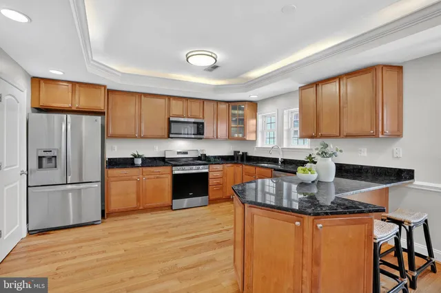 a kitchen with granite countertop wooden floors stainless steel appliances and a window