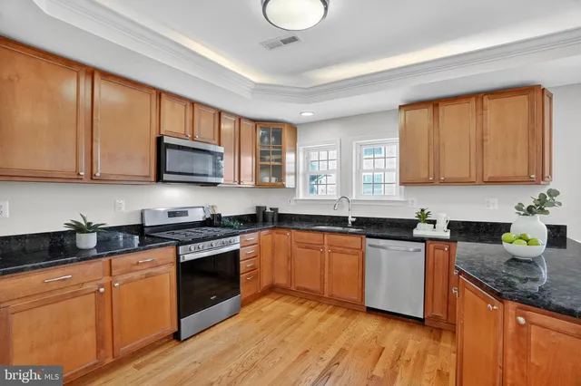 a kitchen with stainless steel appliances granite countertop wooden cabinets a stove a sink and a microwave