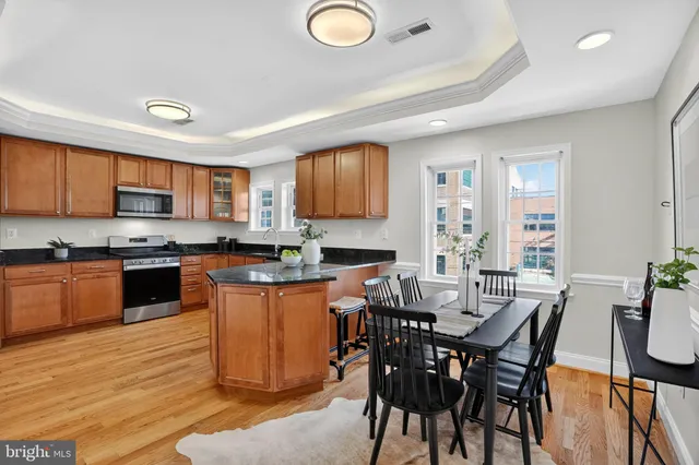a kitchen with granite countertop a table chairs a sink dishwasher stove and cabinets with wooden floor
