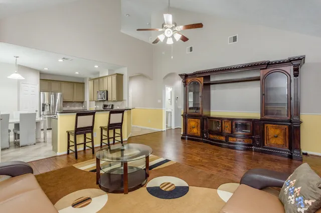 a living room with couches and kitchen view with wooden floor