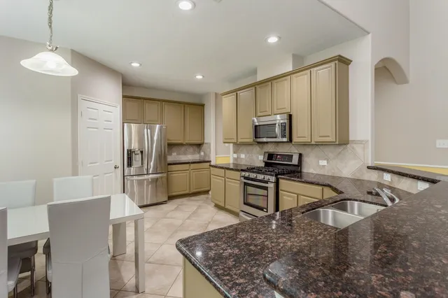 a kitchen with stainless steel appliances granite countertop a sink refrigerator and microwave