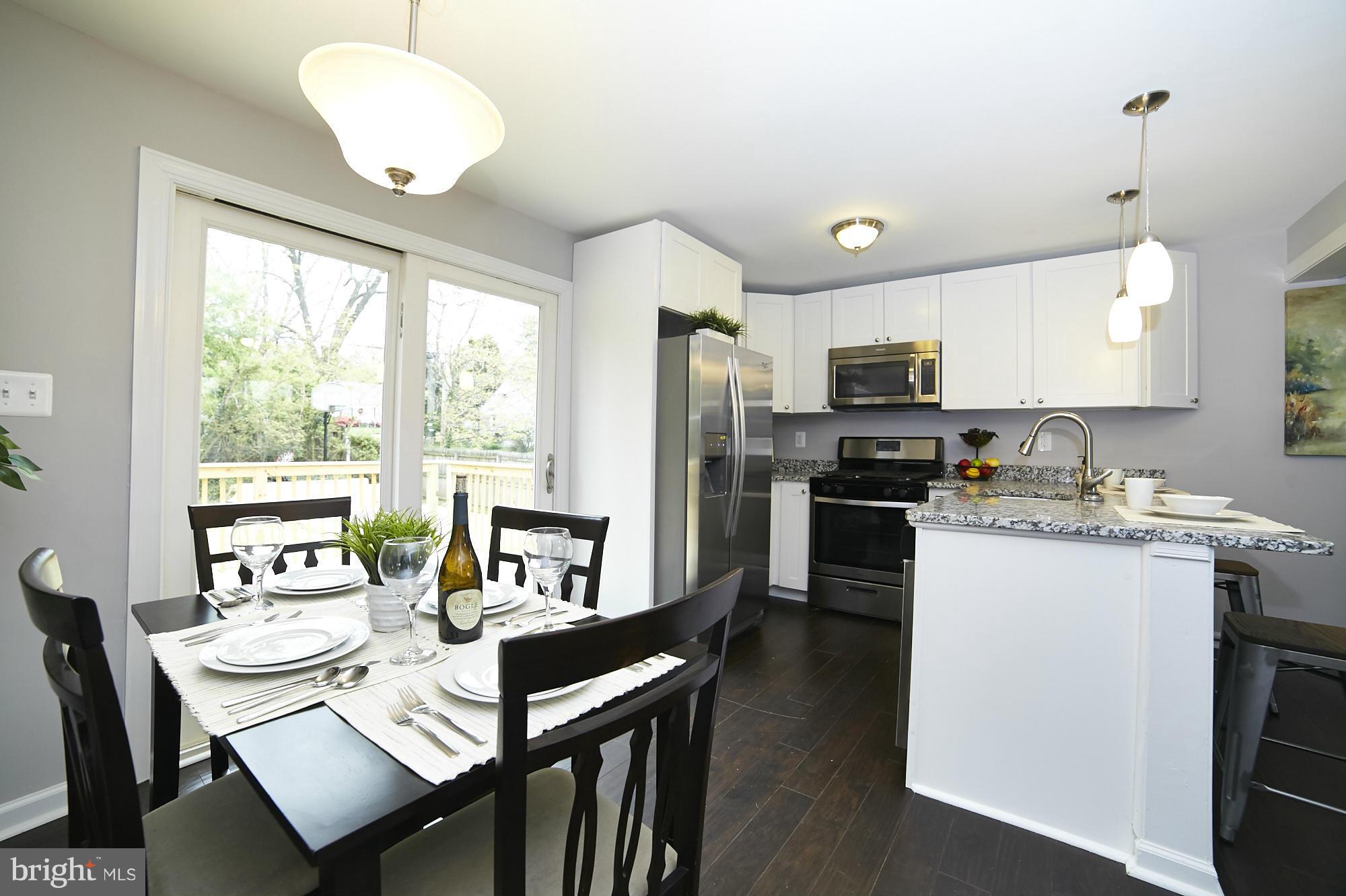 719 Cliffedge Road Baltimore, MD 21208 - Photo 7 of 30 a open kitchen with a refrigerator a stove top oven a sink dishwasher a dining table and chairs with wooden floor