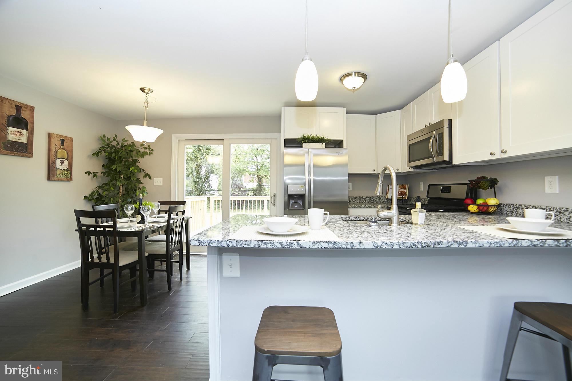719 Cliffedge Road Baltimore, MD 21208 - Photo 9 of 30 a kitchen with granite countertop kitchen island stainless steel appliances a table and chairs in it
