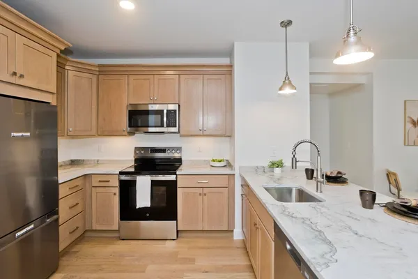 a kitchen with stainless steel appliances granite countertop a sink and a stove top oven with wooden floor