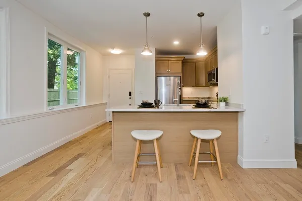 a kitchen with kitchen island granite countertop a sink a stove a dining table and chairs